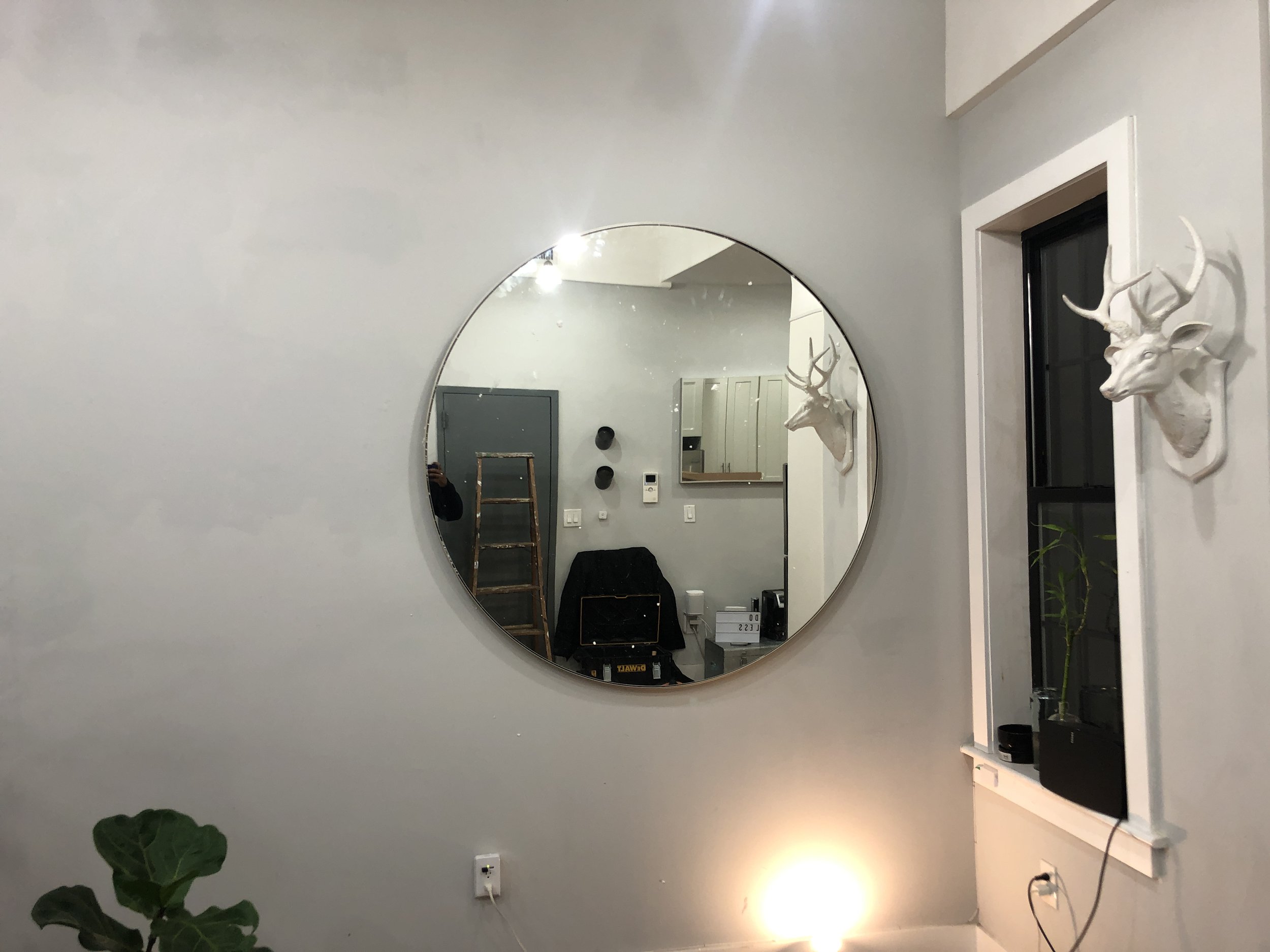 Oval mirror hung on a wall during professional installation. Reliable mirror and artwork mounting in Queens, Brooklyn, and Long Island.